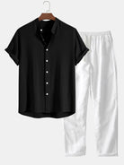 Schwarzes Kurzarmhemd mit weißen Knöpfen, kombiniert mit weißen, locker sitzenden Hosen. Perfekt für lässige Sommermode und stilvolle Outfits.