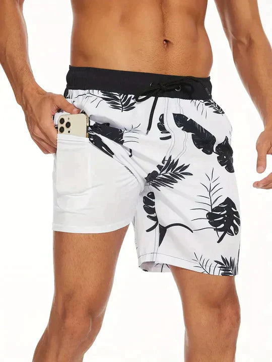 Herren-Badeshorts mit tropischem Muster, weiß-schwarz, Handyfach, Sommermode.