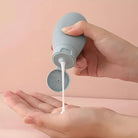 Hand drückt weiße Lotion aus grauer Flasche, Hautpflegeprodukt, minimalistisch, Nahaufnahme.