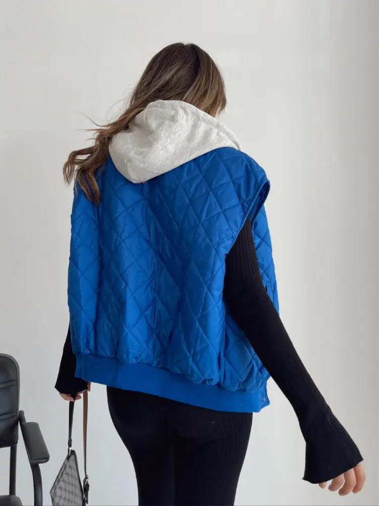 Ärmellose blaue Steppweste für Damen, kombiniert mit weißem Kapuzenpullover. Modetrend, lässiger Stil, ideal für Herbst und Winter.