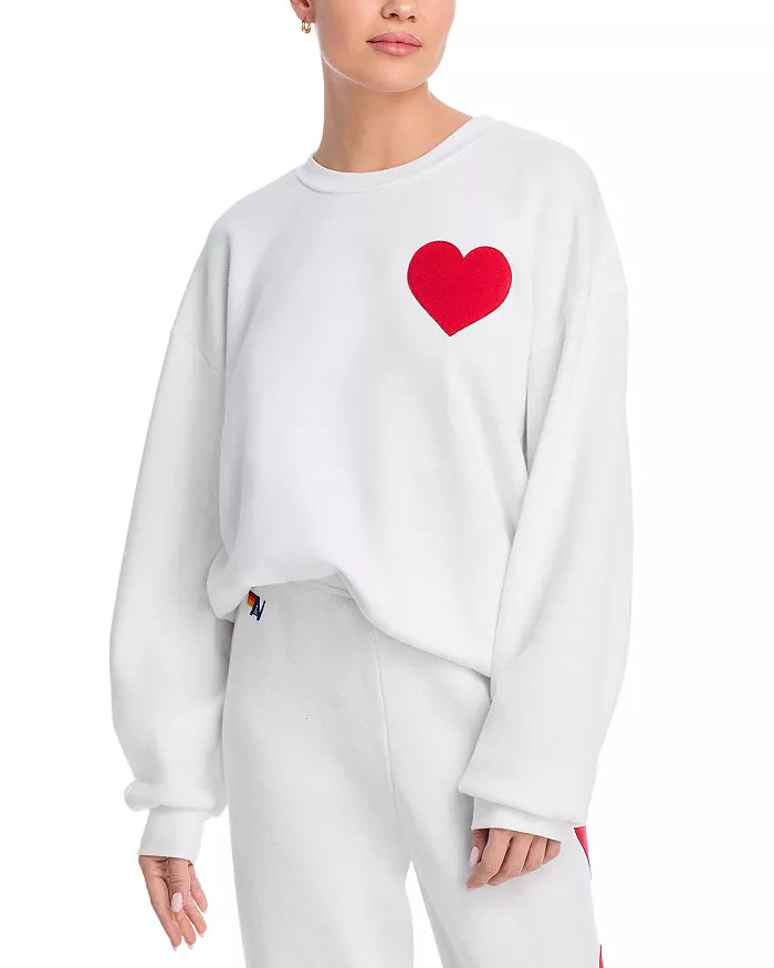Frau in weißem Sweatshirt mit rotem Herzmotiv, lässige Mode, Damenbekleidung, Streetwear.