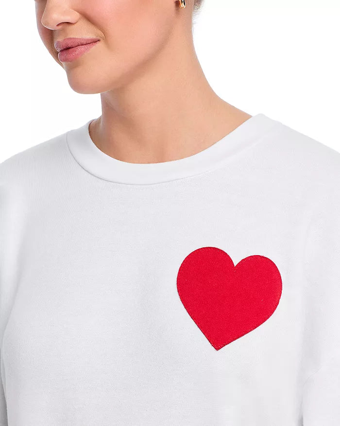 Frau trägt weißes Sweatshirt mit rotem Herzmotiv, Damenmode, lässiger Stil, Baumwolle.