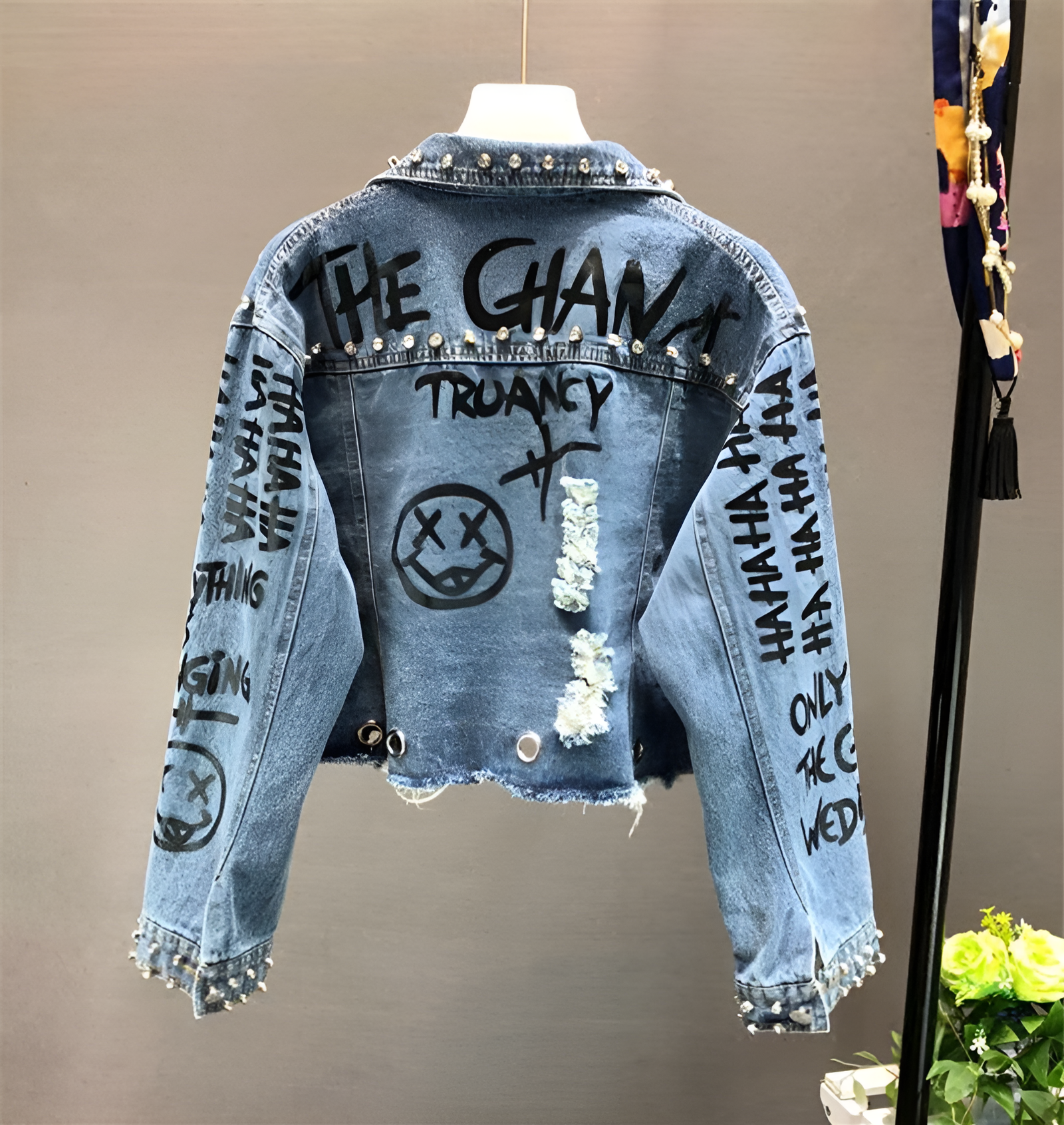 Damen-Jeansjacke mit Graffiti-Design, Nieten und Rissen. Trendige Streetwear, ideal für urbanen Stil. Perfekt für modische Outfits.