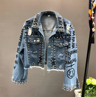 Damen-Jeansjacke mit Nieten, Schriftzügen und Fransen. Modische, zerrissene Denim-Jacke, ideal für trendige Streetwear-Looks.