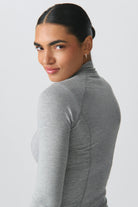 Frau in grauem Rollkragenpullover, lächelnd, mit glattem Haar. Mode, Damenbekleidung, eleganter Look, stilvoll, modern, minimalistisch.