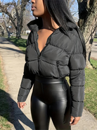 Frau in schwarzer Steppjacke und Lederleggings spaziert im Freien. Modetrend, Wintermode, Damenbekleidung, stilvoll, urban.
