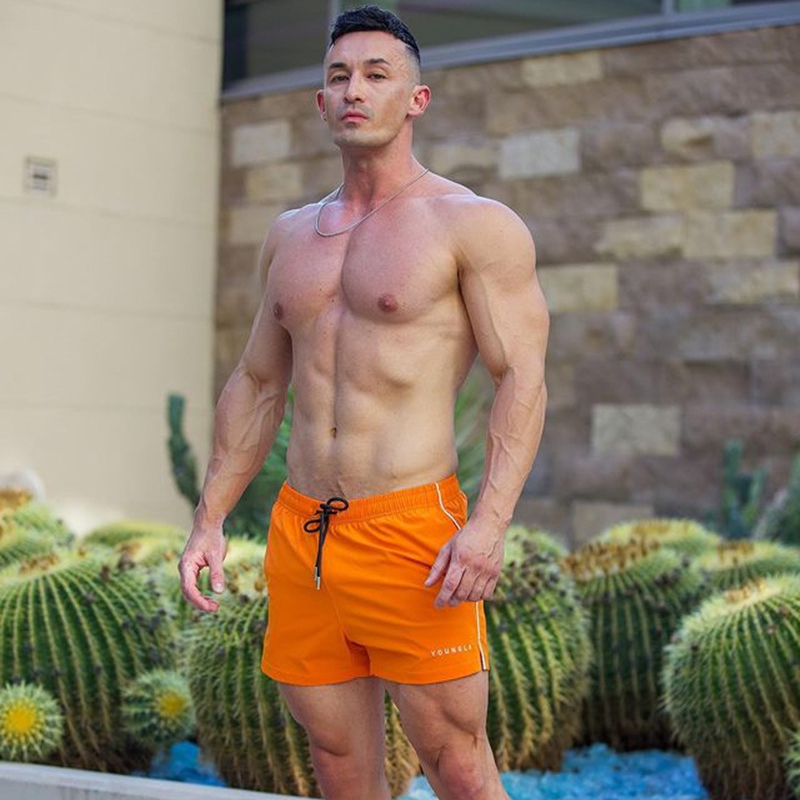 Mann in orange Badehose vor Kaktus, Fitness, Sommermode, Herrenbekleidung, Outdoor.