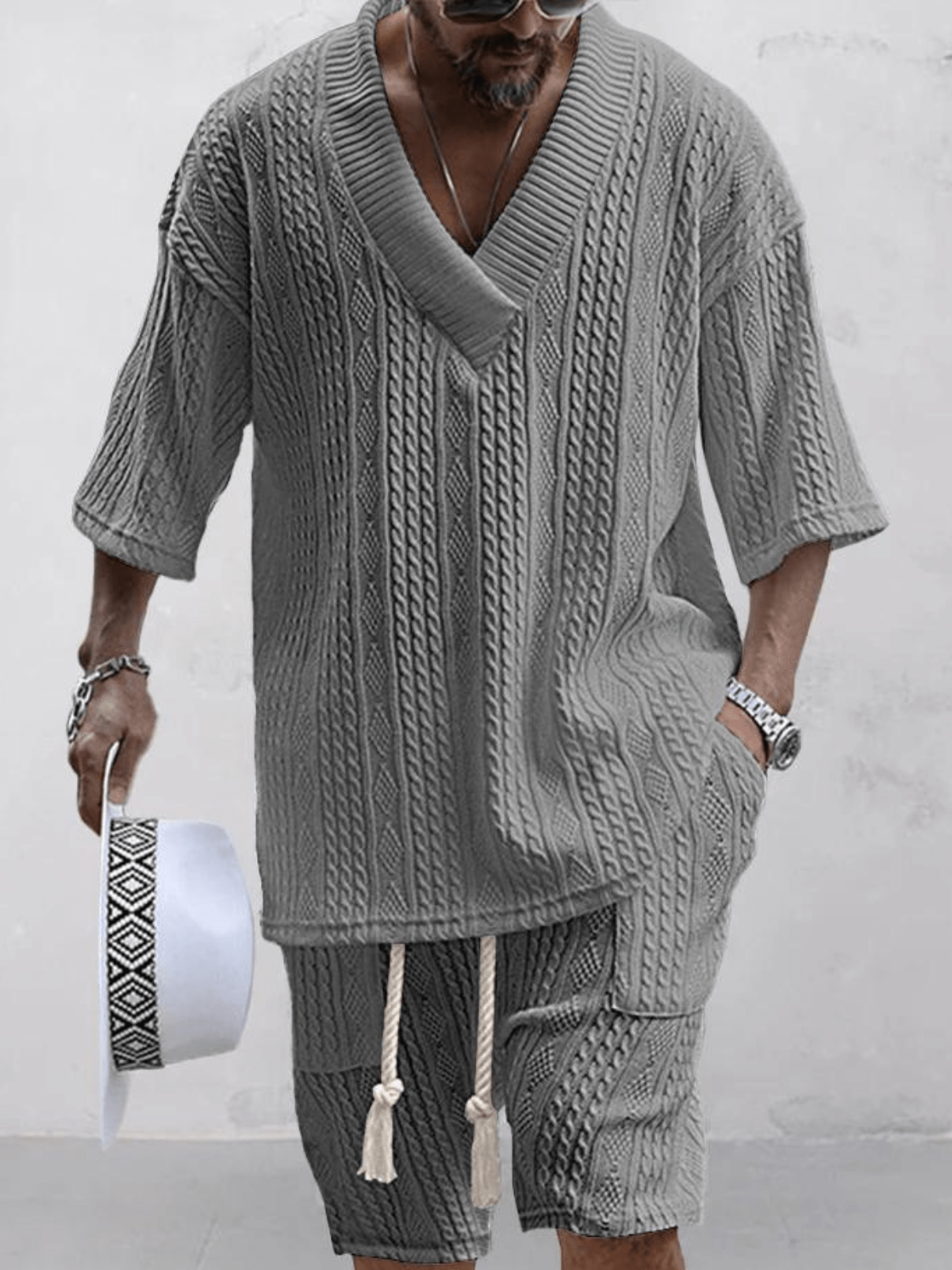 Graues Strickset für Herren mit V-Ausschnitt und kurzen Ärmeln, kombiniert mit passender Shorts. Perfekt für lässige Sommermode und stilvolle Freizeitkleidung.