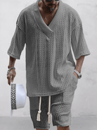 Graues Strickset für Herren mit V-Ausschnitt und kurzen Ärmeln, kombiniert mit passender Shorts. Perfekt für lässige Sommermode und stilvolle Freizeitkleidung.