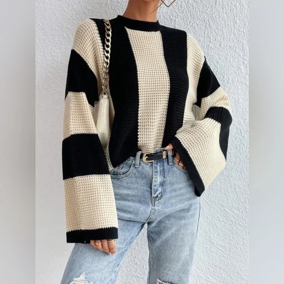 Damenpullover mit schwarz-weißen Blockstreifen, grob gestrickt, kombiniert mit hellblauen Jeans. Modetrend, Herbstmode, lässiger Stil.