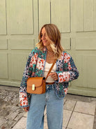 Frau in Vintage-Patchwork-Jacke, Herbstmode 2023. Lässiger Look mit Baumwollmantel, Jeans und brauner Umhängetasche. Trendige Damenbekleidung.