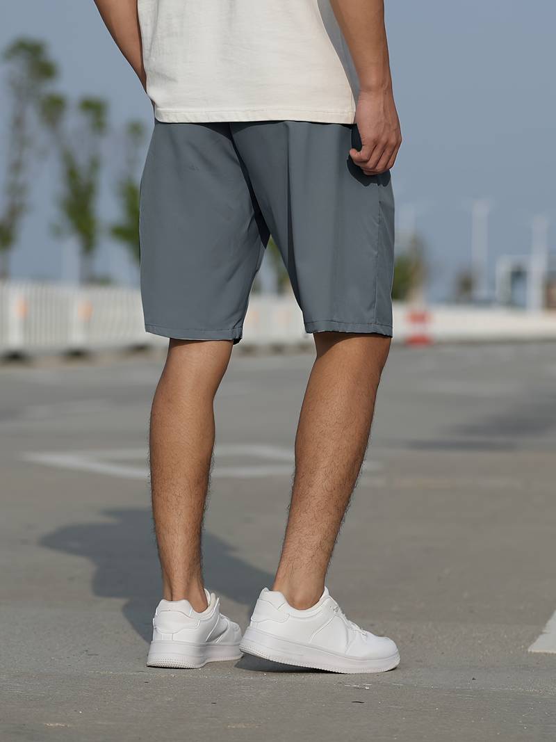 Mann in grauen Shorts und weißen Sneakers auf Straße, Freizeitmode, Sommerbekleidung.