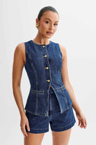 Frau in ärmelloser Jeansweste und Shorts, elegantes Design, goldene Knöpfe, modischer Look, Sommermode, Damenbekleidung, trendiges Outfit.