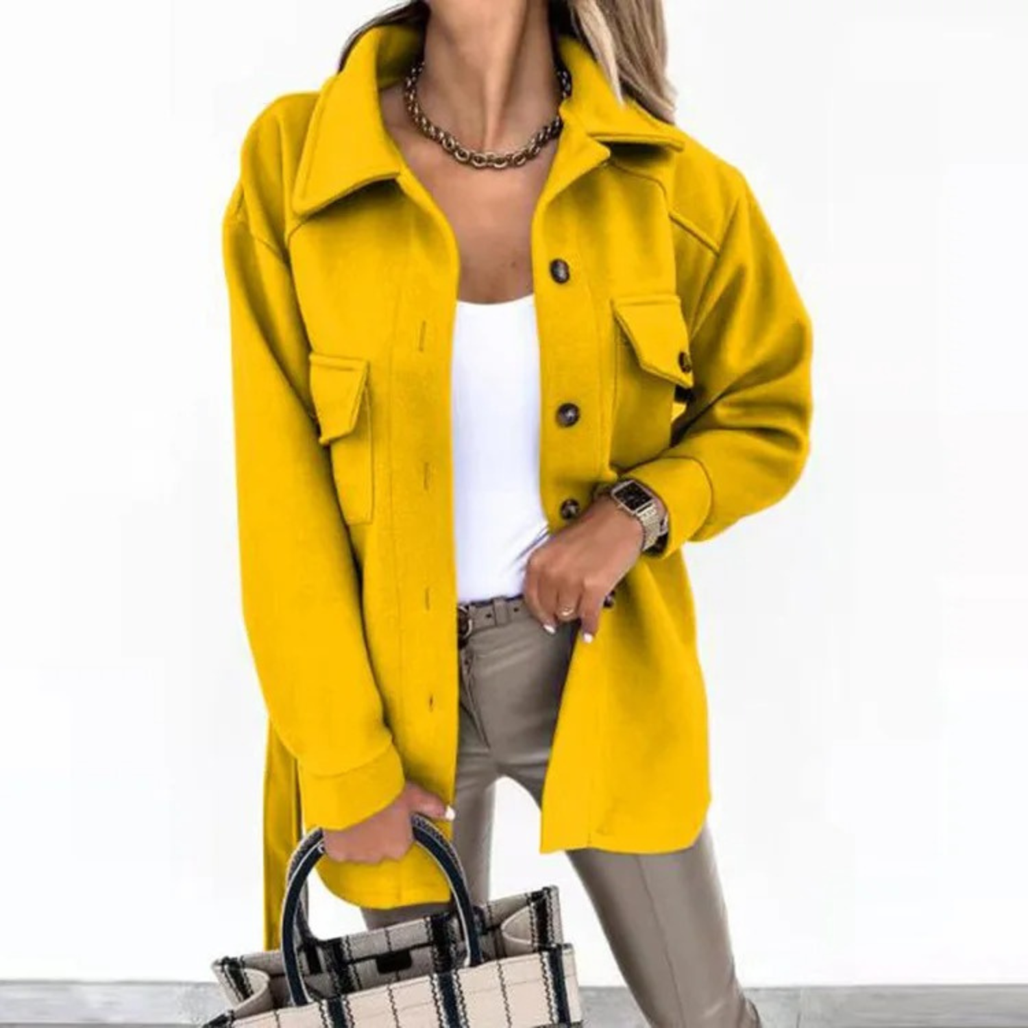 Frau in gelber Jacke, weißem Top und beiger Hose hält eine karierte Handtasche. Modetrend, Damenmode, Herbstoutfit, stilvolle Kleidung.