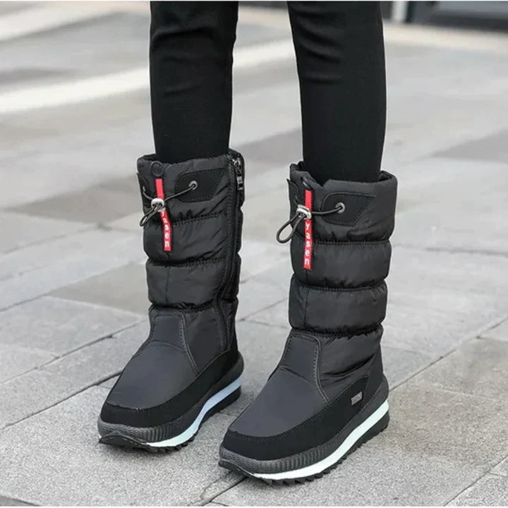 Schwarze Winterstiefel mit dicker Sohle und rotem Detail, ideal für kaltes Wetter. Wasserdicht, warm und modisch für Damen.