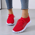 Rote Damen-Sneaker mit weißer Sohle, atmungsaktivem Mesh-Obermaterial und Schnürsenkeln. Perfekt für Sport und Freizeit.