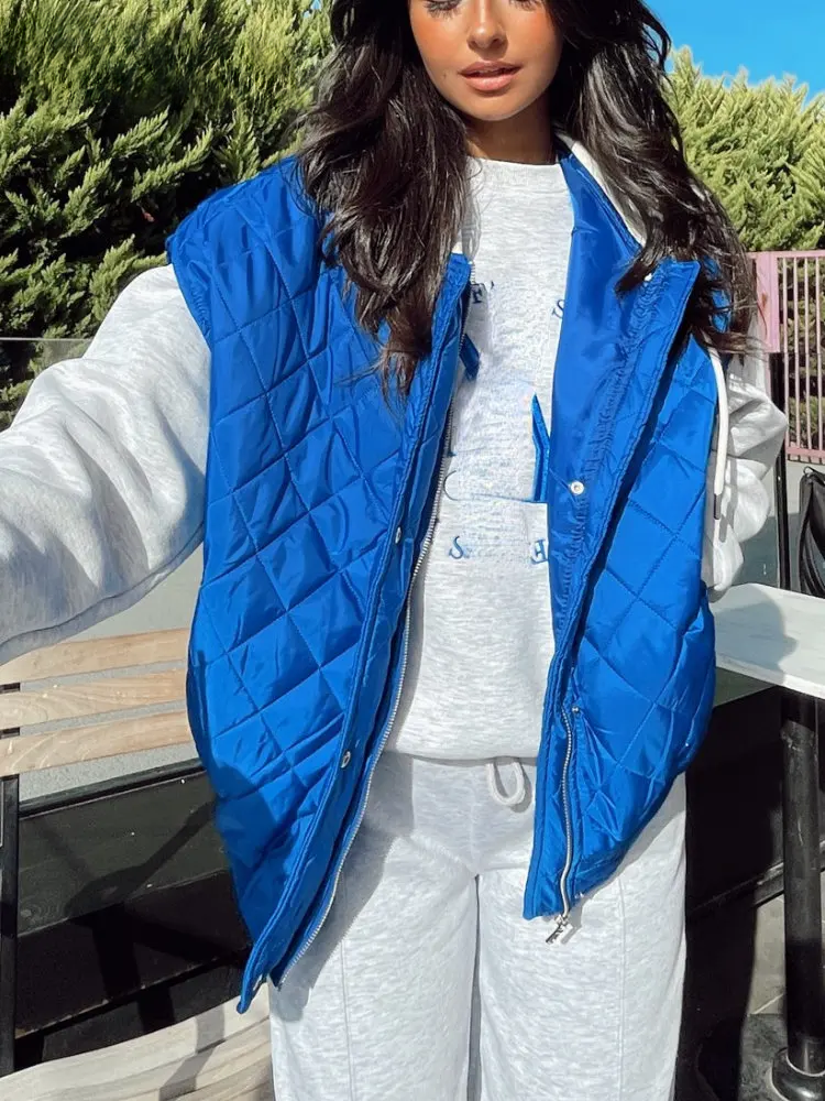 Blaues, ärmelloses Steppweste für Damen mit Reißverschluss, ideal für Herbstmode. Kombiniert mit grauem Freizeitanzug für lässigen Look.