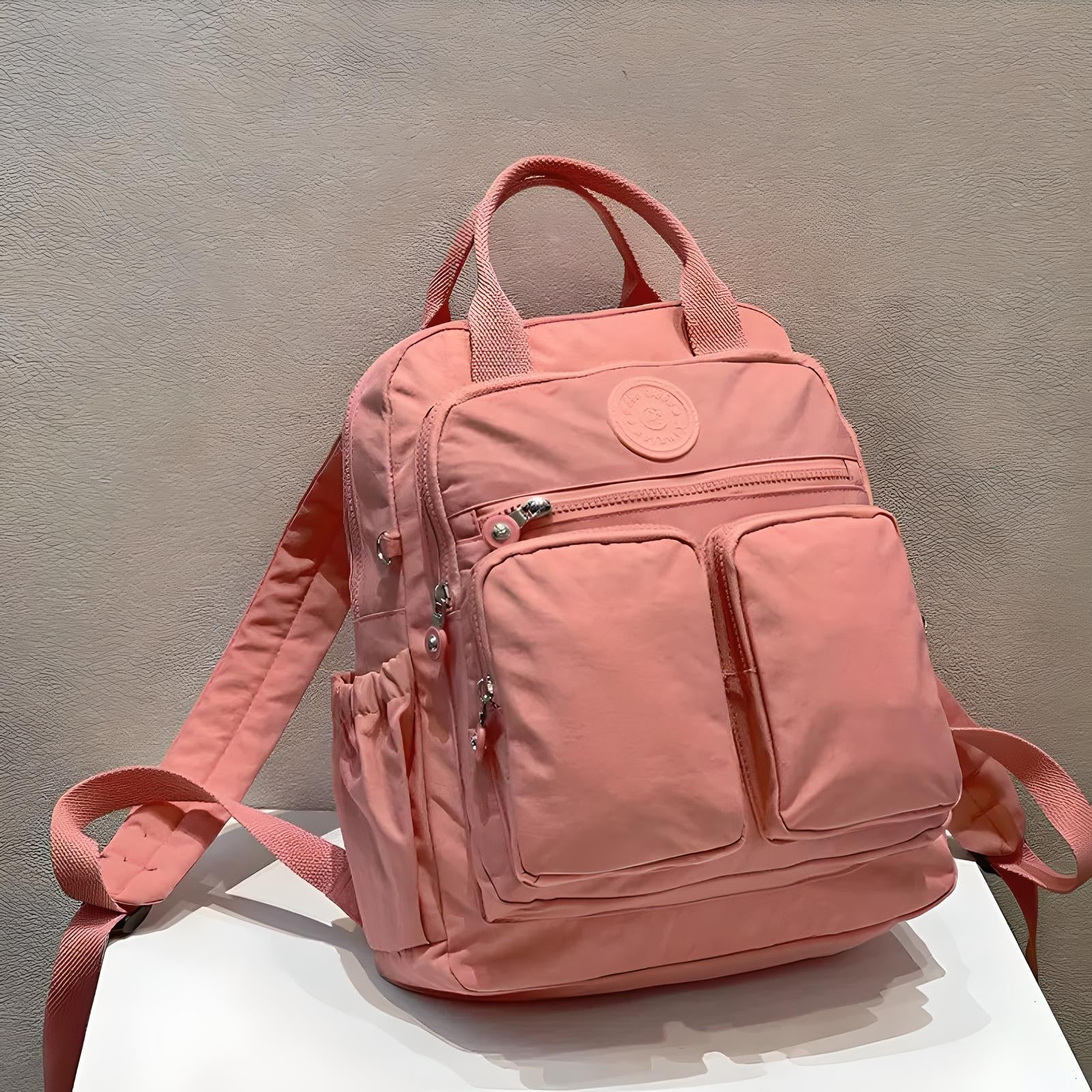 Rosa Rucksack mit mehreren Taschen, Reißverschlüssen, ideal für Schule oder Reisen.