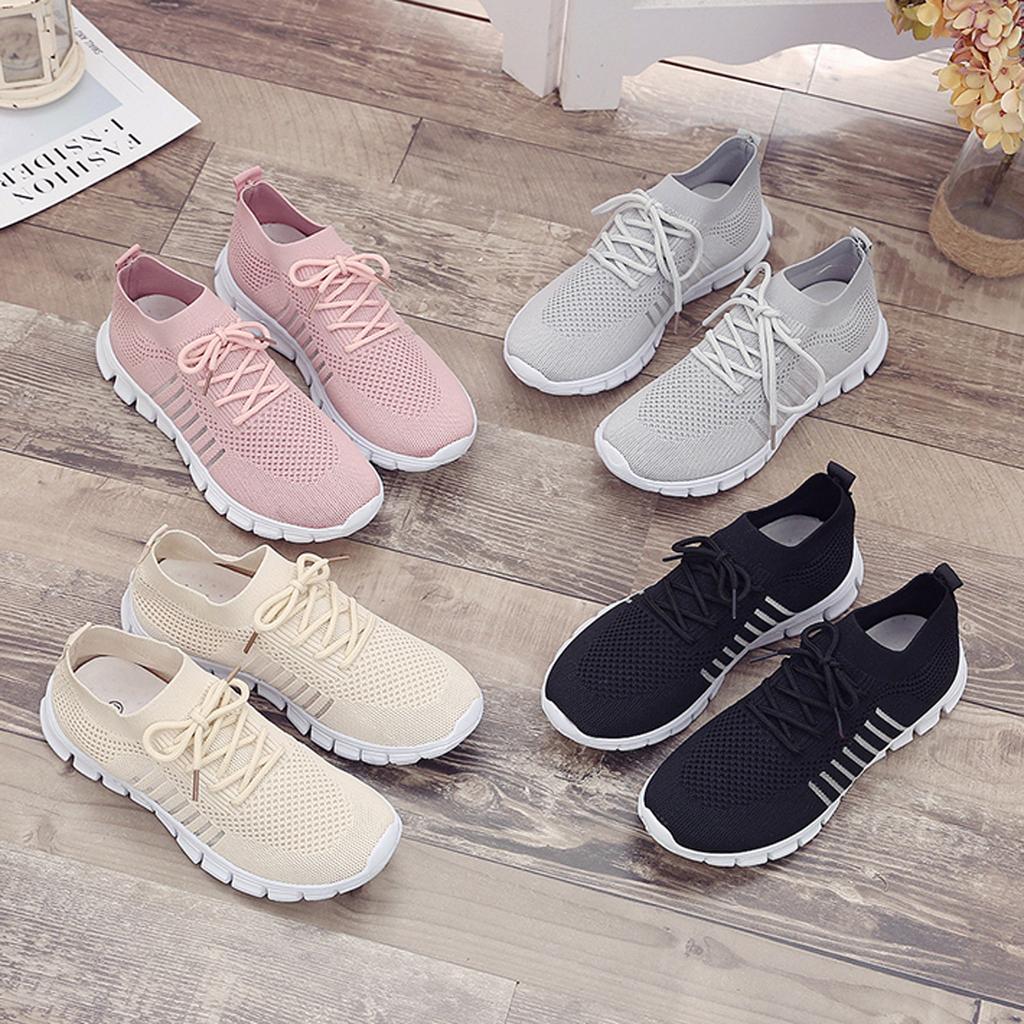 Moderne Sneaker-Kollektion in Pastell- und Neutralfarben auf Holzboden. Atmungsaktive Mesh-Oberfläche, ideal für Freizeit und Sport.