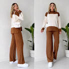 Frau in modischem, zweifarbigem Outfit: braune Hose, creme-brauner Pullover, weiße Sneaker, weiße Tasche. Trendige Damenmode, Herbstlook.