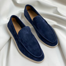Dunkelblaue Wildleder-Slipper für Herren auf weißem Hintergrund, stilvoll und bequem, ideal für Freizeit und Business, rutschfeste Sohle.