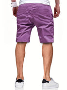 Mann in lila Shorts, weißem T-Shirt und weißen Sneakers von hinten.