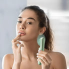 Frau verwendet grünen Gesichtsmassageroller, Hautpflege, Wellness, Entspannung, Beauty-Routine.