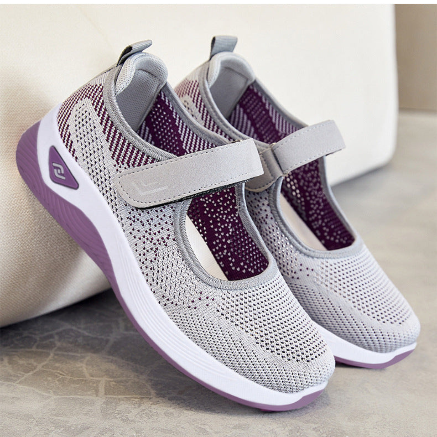 Damen-Sneaker in Grau mit atmungsaktivem Mesh, Klettverschluss und lila Akzenten. Bequeme, modische Schuhe für Alltag und Sport.
