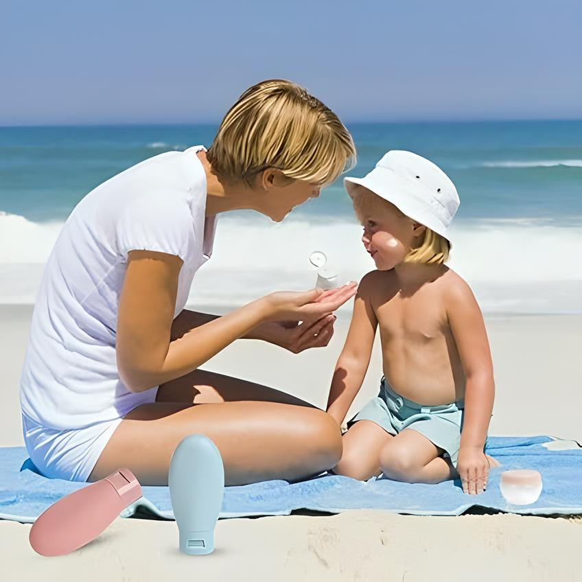 Mutter und Kind am Strand mit Sonnencreme, blaues Handtuch, Sommer, Hautschutz, Meer im Hintergrund.