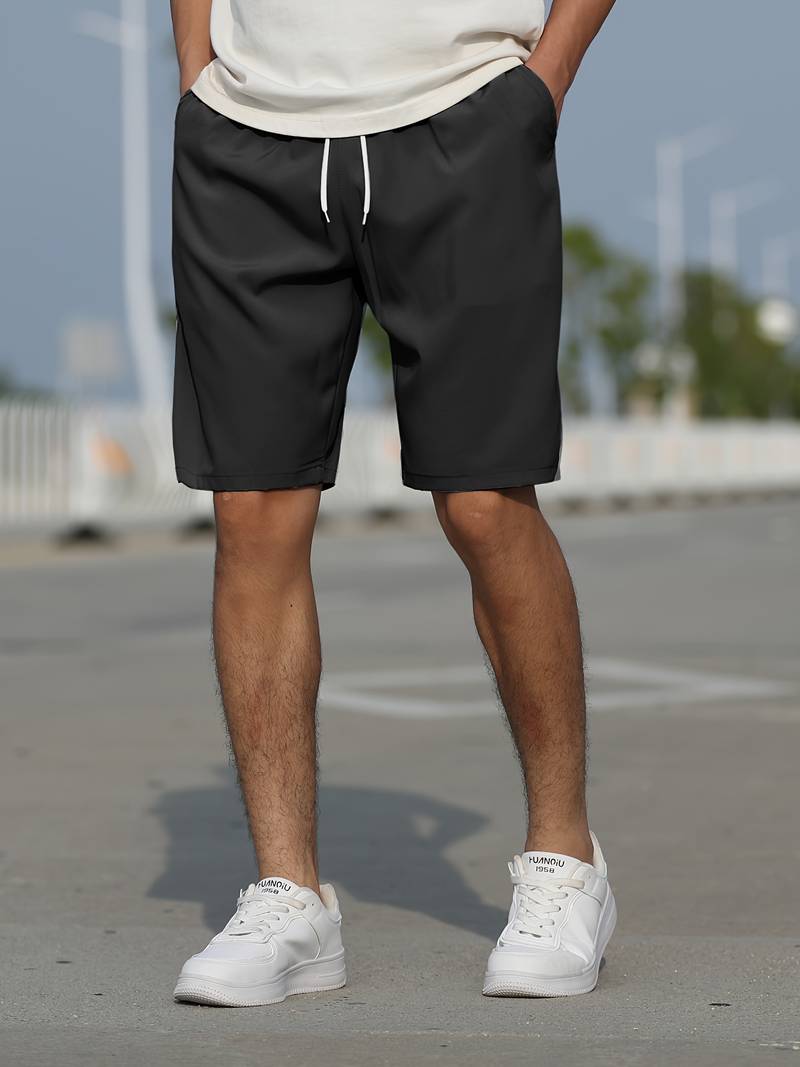Mann trägt schwarze Sportshorts und weiße Sneaker auf Straße, Freizeitmode für Herren.