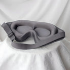 Graue Schlafmaske aus Memory-Schaum, ergonomisch, verstellbar, für erholsamen Schlaf.