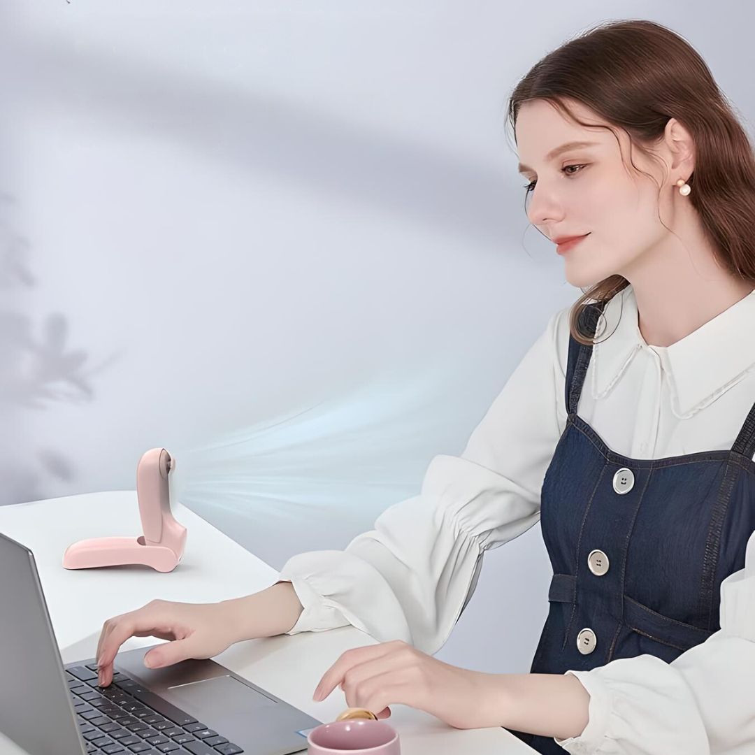 Frau arbeitet am Laptop mit rosa Mini-Luftbefeuchter auf dem Tisch, modernes Home-Office-Setup.