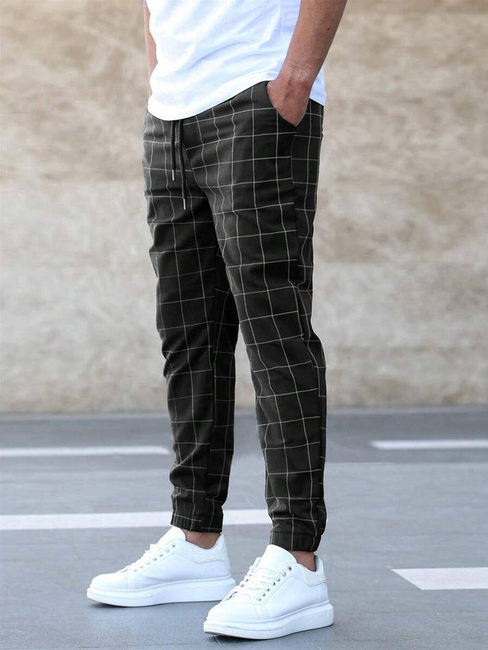 Mann trägt karierte Jogginghose in Schwarz-Weiß mit weißen Sneakern, lässiger Stil.