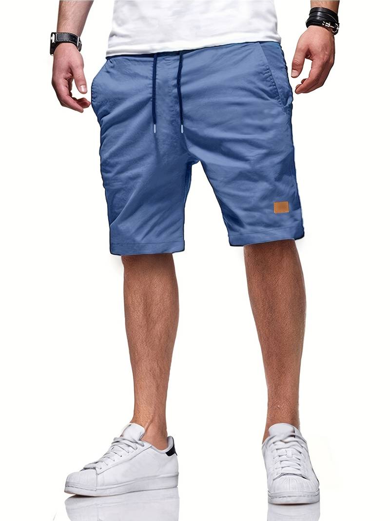 Mann trägt blaue Herren-Shorts, lässig, mit Taschen, kombiniert mit weißen Sneakers.