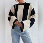 Damenpullover mit schwarz-weißen Blockstreifen, grob gestrickt, kombiniert mit blauer Jeans. Modetrend, Herbstmode, lässiger Stil.