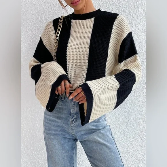 Damenpullover mit schwarz-weißen Blockstreifen, grob gestrickt, kombiniert mit blauer Jeans. Modetrend, Herbstmode, lässiger Stil.