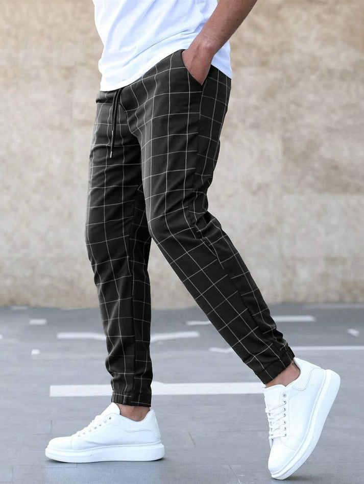 Mann trägt karierte Jogginghose in Schwarz-Weiß mit weißen Sneakern, lässiger Stil.