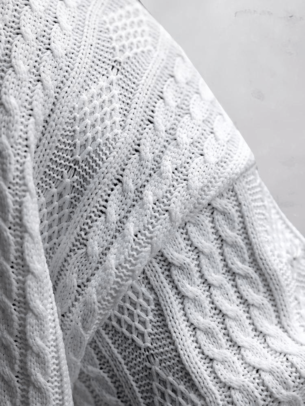 Weiße Strickdecke mit Zopfmuster, weiche Textur, ideal für gemütliche Wohnräume. Hochwertige Baumwolle, stilvolles Design, perfekte Heimdekoration.