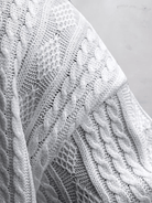 Weiße Strickdecke mit Zopfmuster, weiche Textur, ideal für gemütliche Wohnräume. Hochwertige Baumwolle, stilvolles Design, perfekte Heimdekoration.