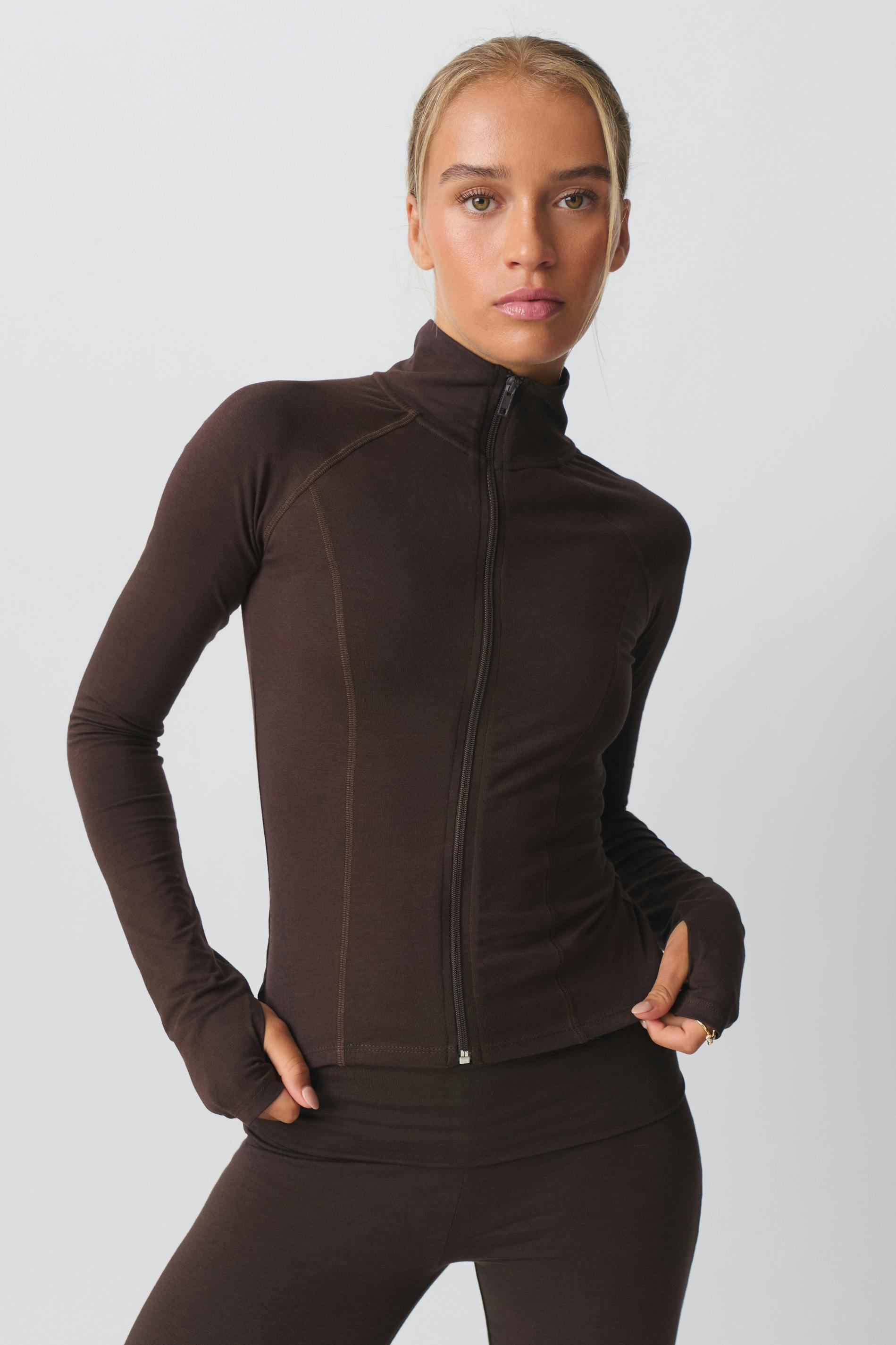 Damen-Sportjacke in Dunkelbraun, figurbetont, mit Reißverschluss und Stehkragen. Perfekt für Fitness, Yoga und Freizeitmode.