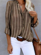 Gestreifte Damenbluse in Braun mit V-Ausschnitt und langen Ärmeln, kombiniert mit weißer Hose. Modetrend, lässiger Look, stilvolle Damenmode.