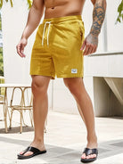Mann in gelber Cord-Shorts mit Kordelzug, tätowierter Arm, schwarze Sandalen, Sommermode.