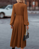 Damenkleid in Braun, langärmelig, fließend, elegantes Design. Perfekt für Herbstmode, kombiniert mit schwarzer Handtasche. Ideal für stilvolle Anlässe.
