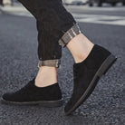 Schwarze Wildleder-Herrenschuhe, lässig, elegant, Straßenhintergrund, modische Herrenmode.