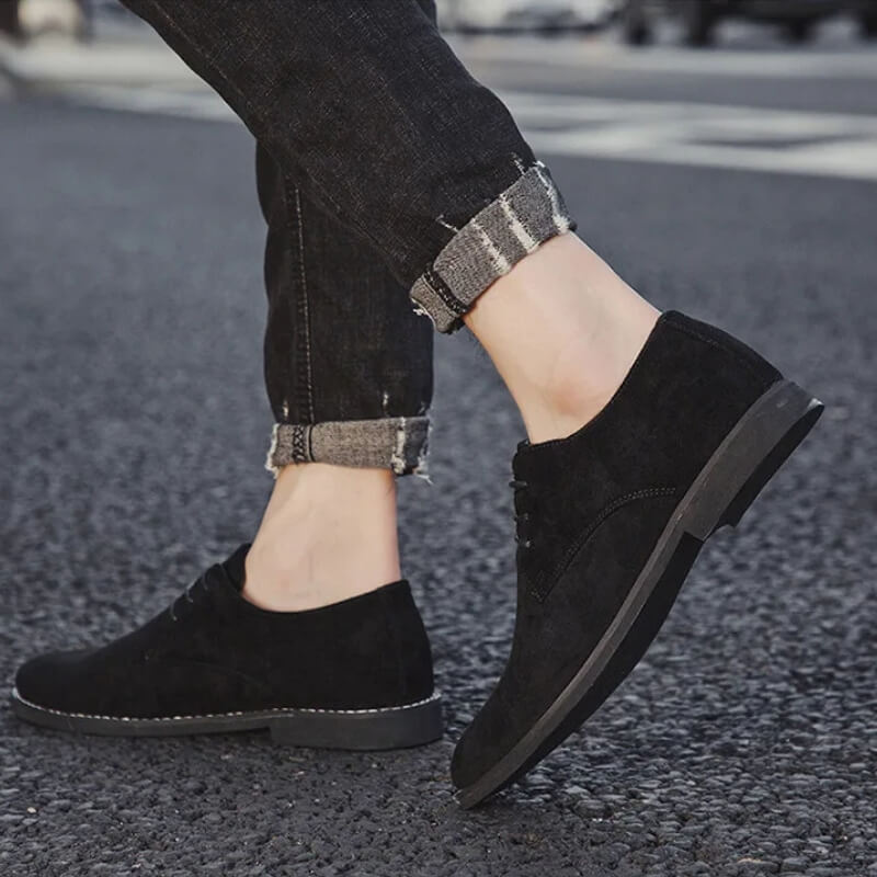 Schwarze Wildleder-Herrenschuhe, lässig, elegant, Straßenhintergrund, modische Herrenmode.