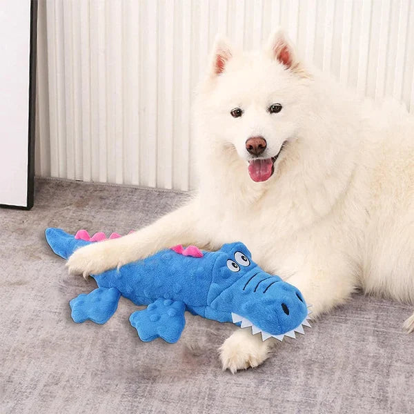 Weißer Hund mit blauem Krokodil-Plüschtier. Perfektes Hundespielzeug, langlebig und sicher. Ideal für Haustierliebhaber und Hundebesitzer.