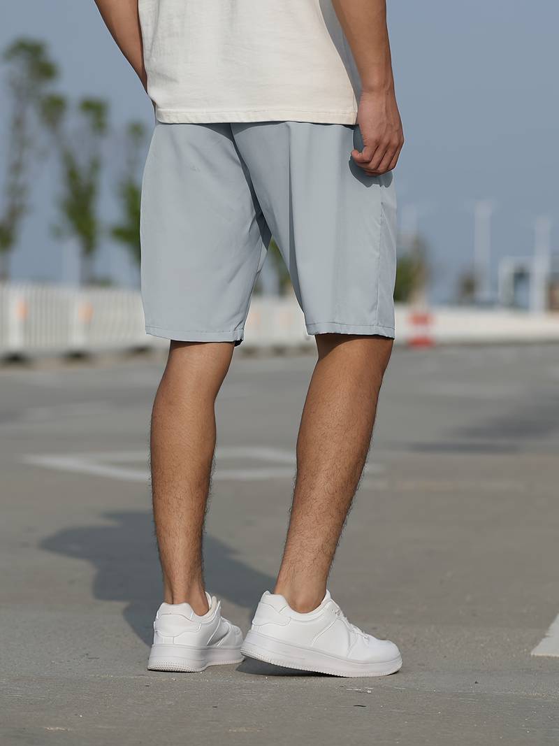 Mann in hellgrauen Shorts und weißen Sneakers auf Straße, Freizeitmode, Sommerbekleidung.