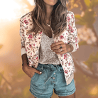 Frau in floraler Bomberjacke, Pailletten-Top und Jeansshorts. Modetrend, lässiger Sommerlook, stilvolle Damenmode, Freizeitoutfit.