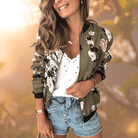 Frau in modischer Blumen-Bomberjacke, weißem Spitzen-Top und Jeansshorts. Trendige Damenmode, lässiger Sommerlook, stilvolle Freizeitkleidung.