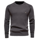 Grauer Herrenpullover mit Karomuster, Rundhalsausschnitt und langen Ärmeln. Stilvoller Strickpullover, ideal für Herbstmode und Freizeitkleidung.